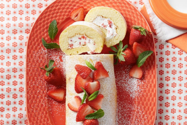 strawberry cream roll topped with strawberries sitting on a red plate