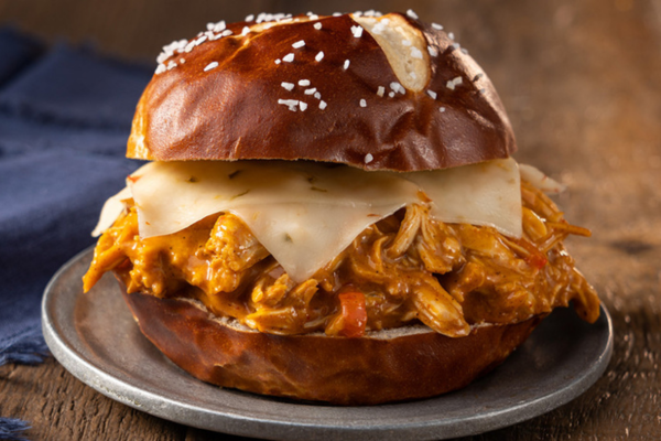 Close up shot a pretzel bun sandwich on a plate