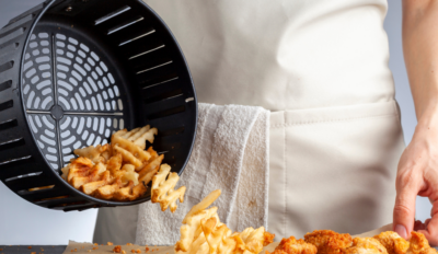 person pouring out food from an air fryer basket onto the counter
