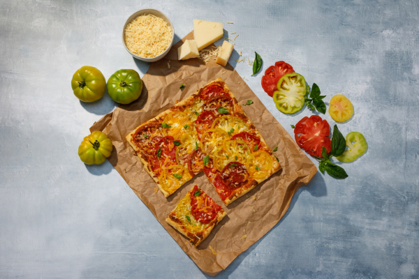 Overhead shot of 3-Cheese Summer Tomato Tart surrounded by tomatoes and parmesan cheese