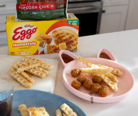 waffles cut into fries sitting on a cutting board next to a cat shaped plate with waffle fries and chicken bites on it