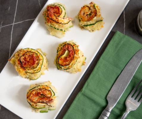 Overhead shot of a breaded zucchini roll-ups on a white plate