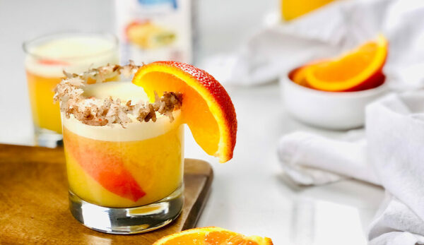 Coconut Creamsicle Cocktail in glass with orange wedge