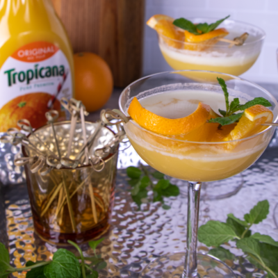 Close up of a martini glass filled with orange creamsicle mocktail garnished with orange and mint